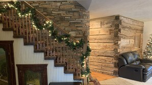 A staircase with a stone wall, a fireplace, and a leather sofa. - Log Inn on Madison Lake.   Multi generation. Corporate retreat for team building (Madison lake)