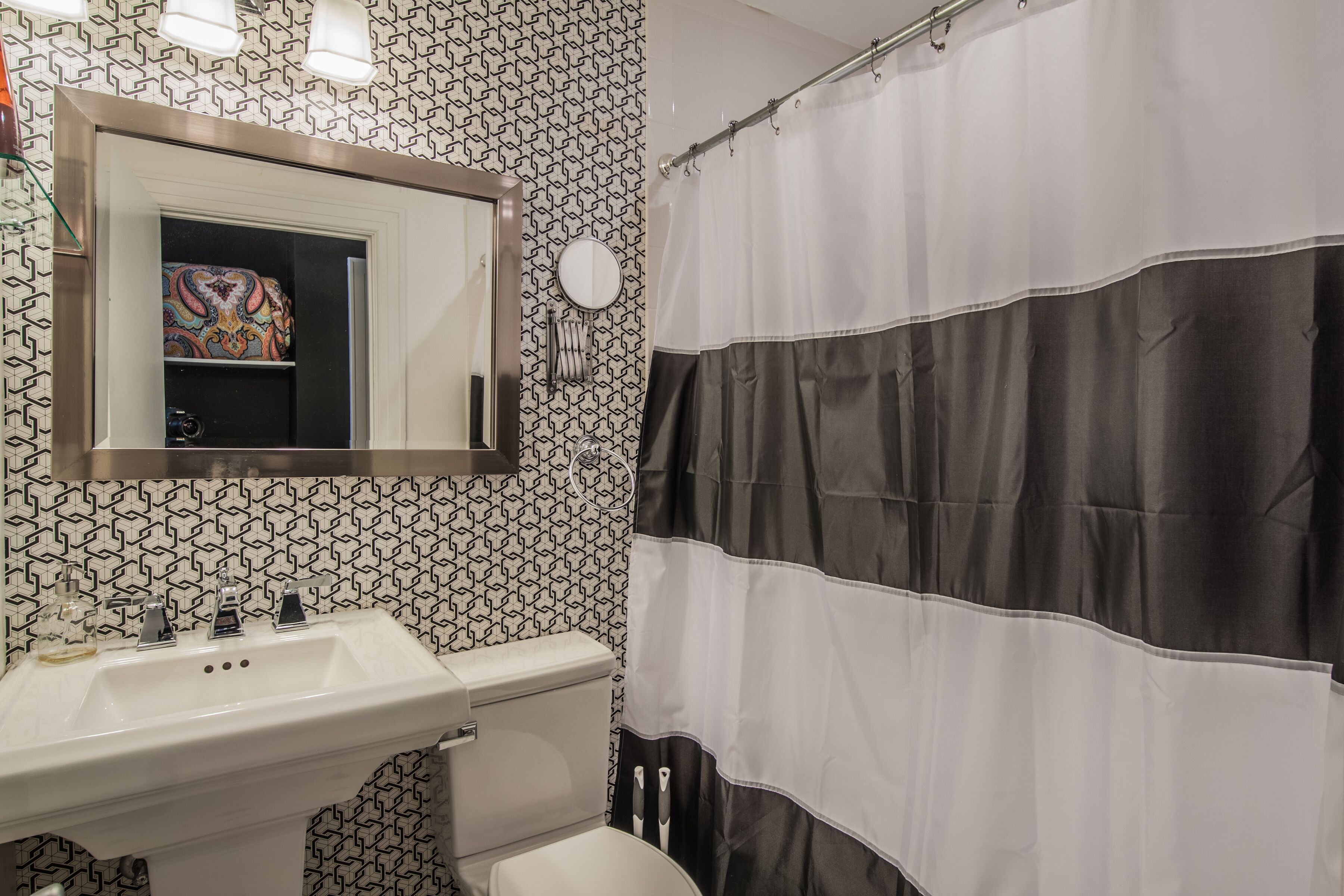 Een badkamer met een witte wastafel, een spiegel, een toilet en een douchegordijn.