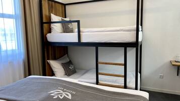 A bunk bed with a ladder, a bedside table, and a window with curtains.