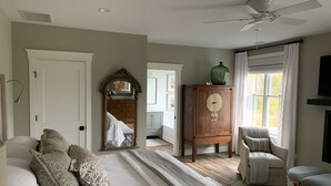 A bedroom with a large bed, a wooden wardrobe, a chair, and a ceiling fan. - The Farmhouse (Hammonton)