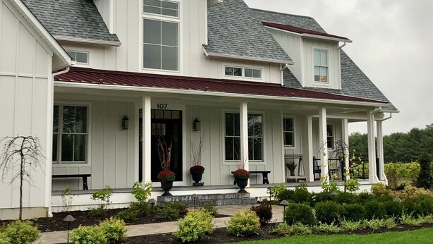 A large, two-story house with a prominent front porch, a number '107' sign, and a well-maintained garden. - The Farmhouse (Hammonton)