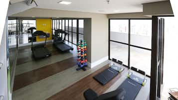 Un gimnasio con cintas de correr, una banca y un juego de mancuernas.