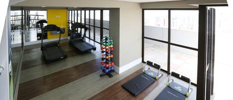 A gym with treadmills, a bench, and a set of dumbbells.