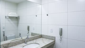 Un baño moderno con lavamanos de granito, un espejo, un inodoro y un teléfono.