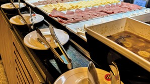 Un bufé con diversos alimentos, entre ellos frutas, quesos y embutidos.