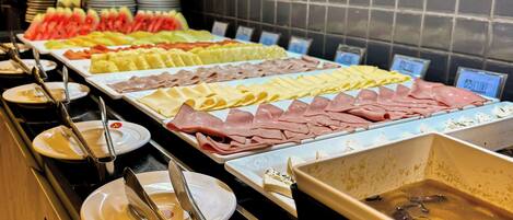 A buffet with various food items including fruits, cheeses, and meats.
