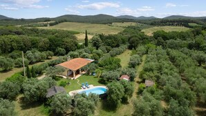 Eine Villa mit Swimmingpool, umgeben von Olivenhainen und Hügeln.