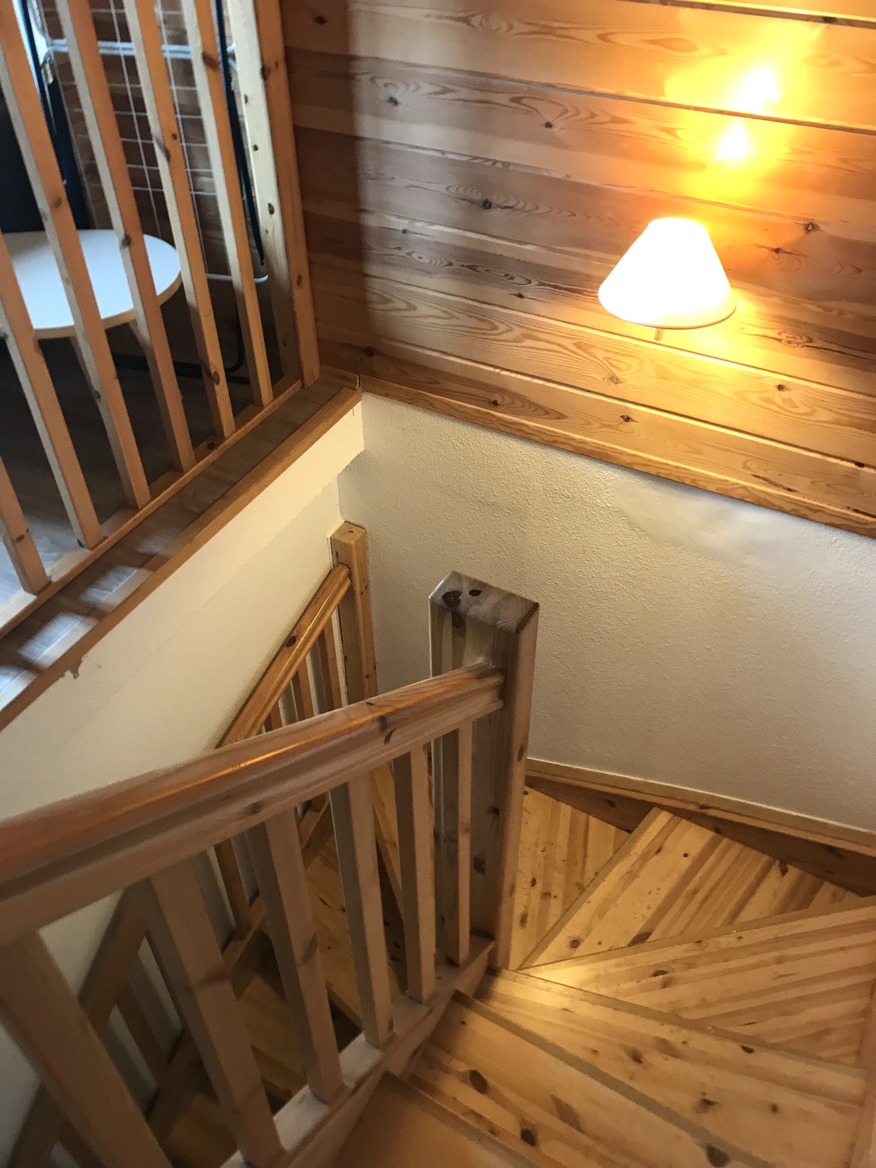 Eine Holztreppe mit Geländer, eine Holzvertäfelung und eine Leuchte.