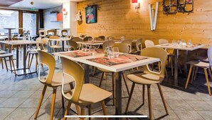 Un restaurant aux murs en bois, doté de nombreuses tables et chaises, et offrant une vue sur l’extérieur grâce à une grande fenêtre.