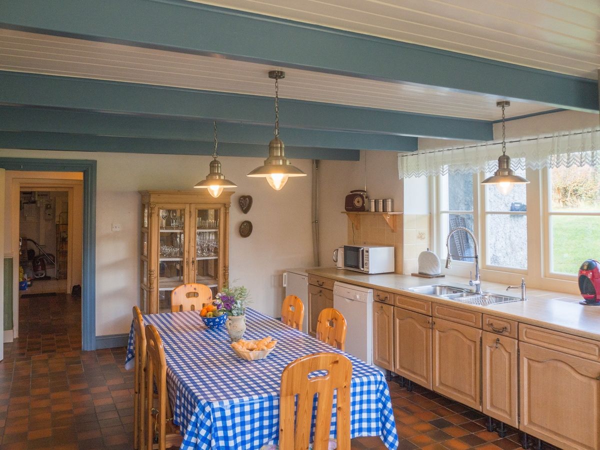 Una cocina con mantel a cuadros, sillas de madera, microondas y un lavabo.