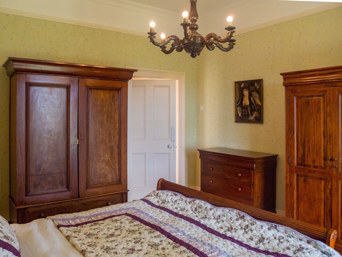 A bedroom with a bed, wooden wardrobe, and a dresser.