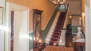 Eine prächtige Treppe mit einem gemusterten Teppich, einer Chandelier und einer Büstenstatue.