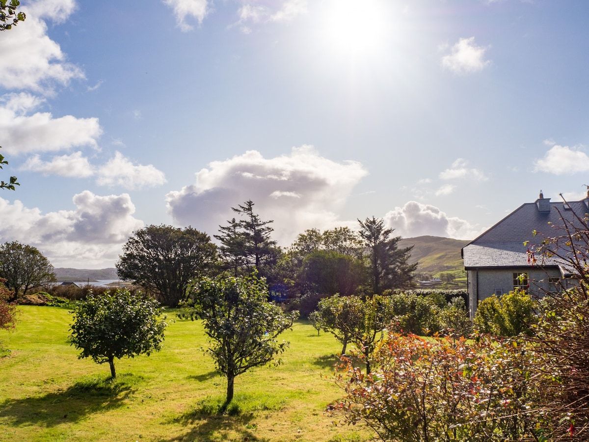 A grassy landscape with trees and a building.