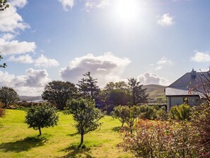A grassy landscape with trees and a building.