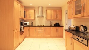 Una cocina moderna con armarios de madera, una campana extractora de acero inoxidable, un microondas y un tostador.