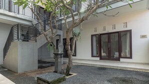 A modern building with a staircase, a tree, and a door with glass panels. - Azalea Homestay & Villa (Canggu)