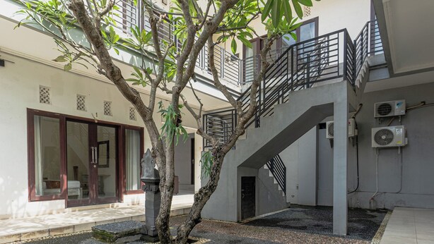 A building with a staircase, air conditioning units, and a tree in the courtyard. - Azalea Homestay & Villa (Canggu)
