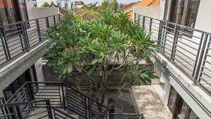 A multi-level building with a central staircase surrounded by metal railings and a tree. - Azalea Homestay & Villa (Canggu)