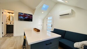 Una cocina moderna con encimera blanca, horno integrado y un armario azul oscuro.