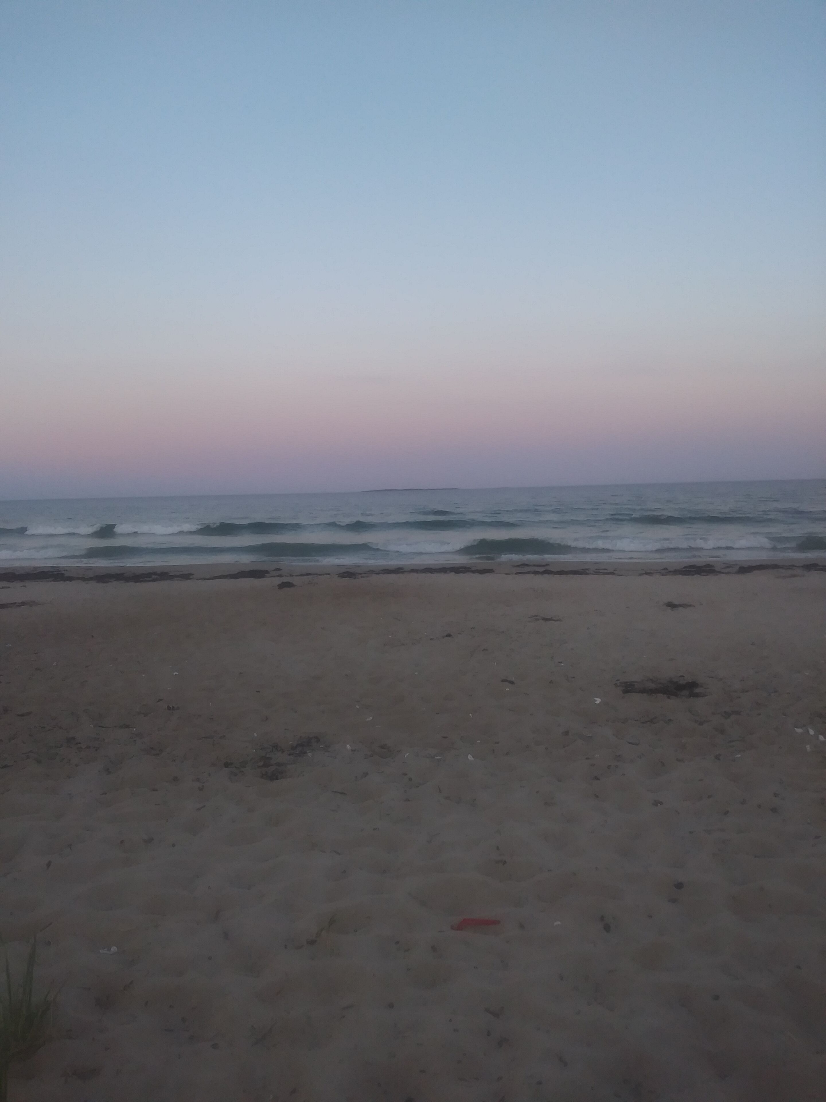 A beach with a clear sky and calm sea.