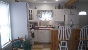 A modern kitchen with white cabinets, a wooden dining table, and a small island with bar stools.