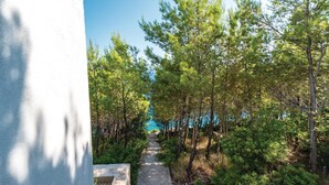 A pathway leading through a forested area with a view of the sea in the distance. - Awesome home in Smokvica (Smokvica)