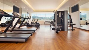 A modern gym with treadmills, elliptical machines, and weight equipment.