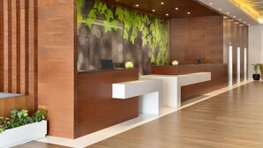 A reception area with wooden paneling, a green leaf-patterned wall, and a modern reception desk.