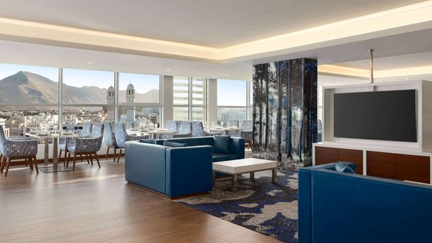 A spacious living area with a large window offering a city view and a mountain in the distance.