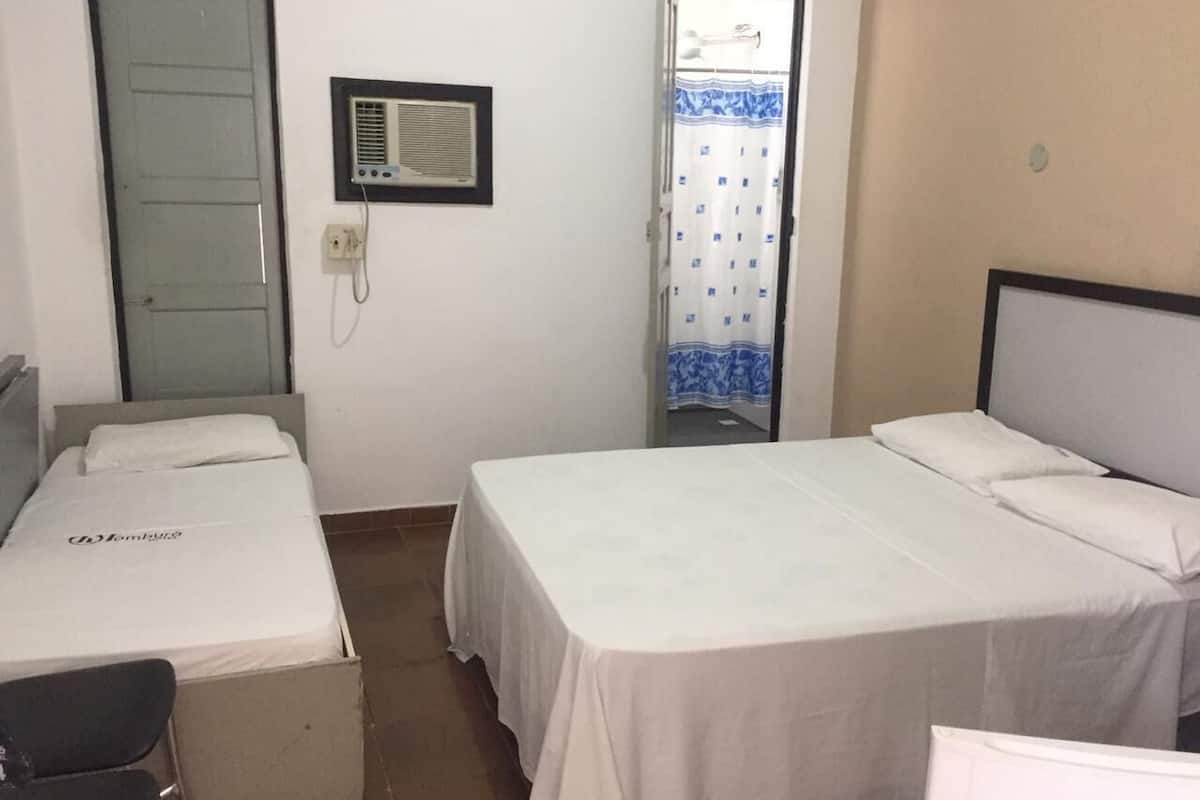 A small, clean room with two single beds, a desk, and a chair.