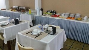 A buffet setup with multiple tables, each with plates, cutlery, and beverages. - Samburá Hotel - Feira de Santana (Feira de Santana)