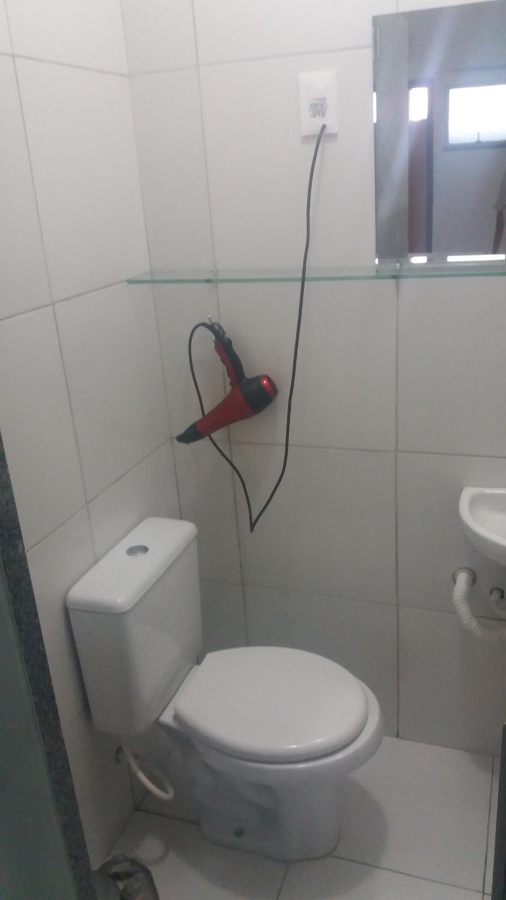 Un bagno piccolo con il water, uno scaffale in vetro e un soffione doccia.