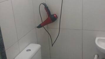 Un bagno piccolo con il water, uno scaffale in vetro e un soffione doccia.