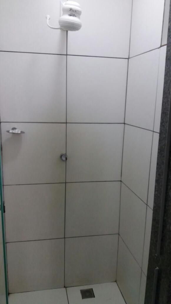 Cabina de dutxa amb rajoles i plat de roba amb dutxadora de mà.