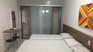 A hotel room with a bed, a desk, and a chair. There is a bathroom with a shower and a sink. - Samburá Hotel - Feira de Santana (Feira de Santana)