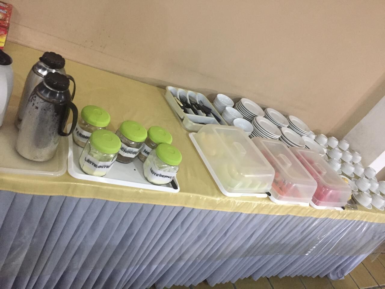 Una mesa de buffet con salsas, cubiertos y recipientes.