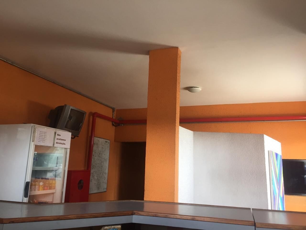 Una habitación con paredes naranjas, techo blanco y un refrigerador blanco con una nota.