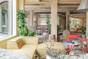 A modern office space with a large window, multiple chairs, tables, and various plants. - Locke At Broken Wharf (London)