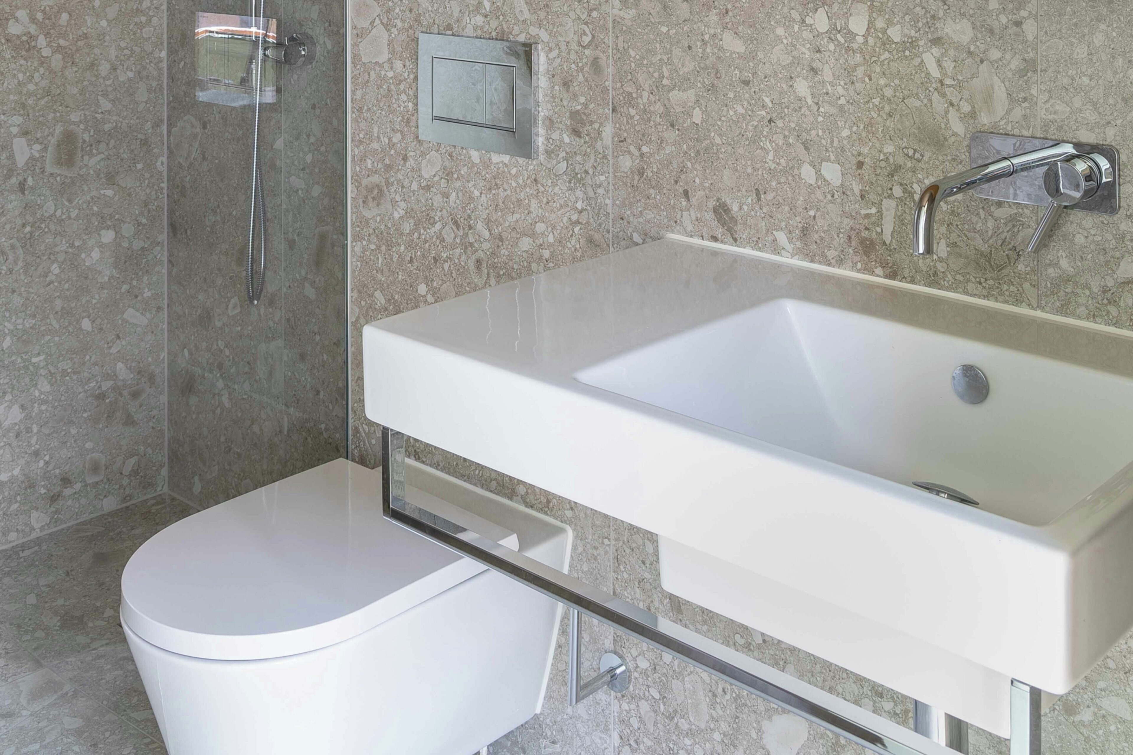 A modern bathroom with a white toilet, a rectangular sink, and a shower area.