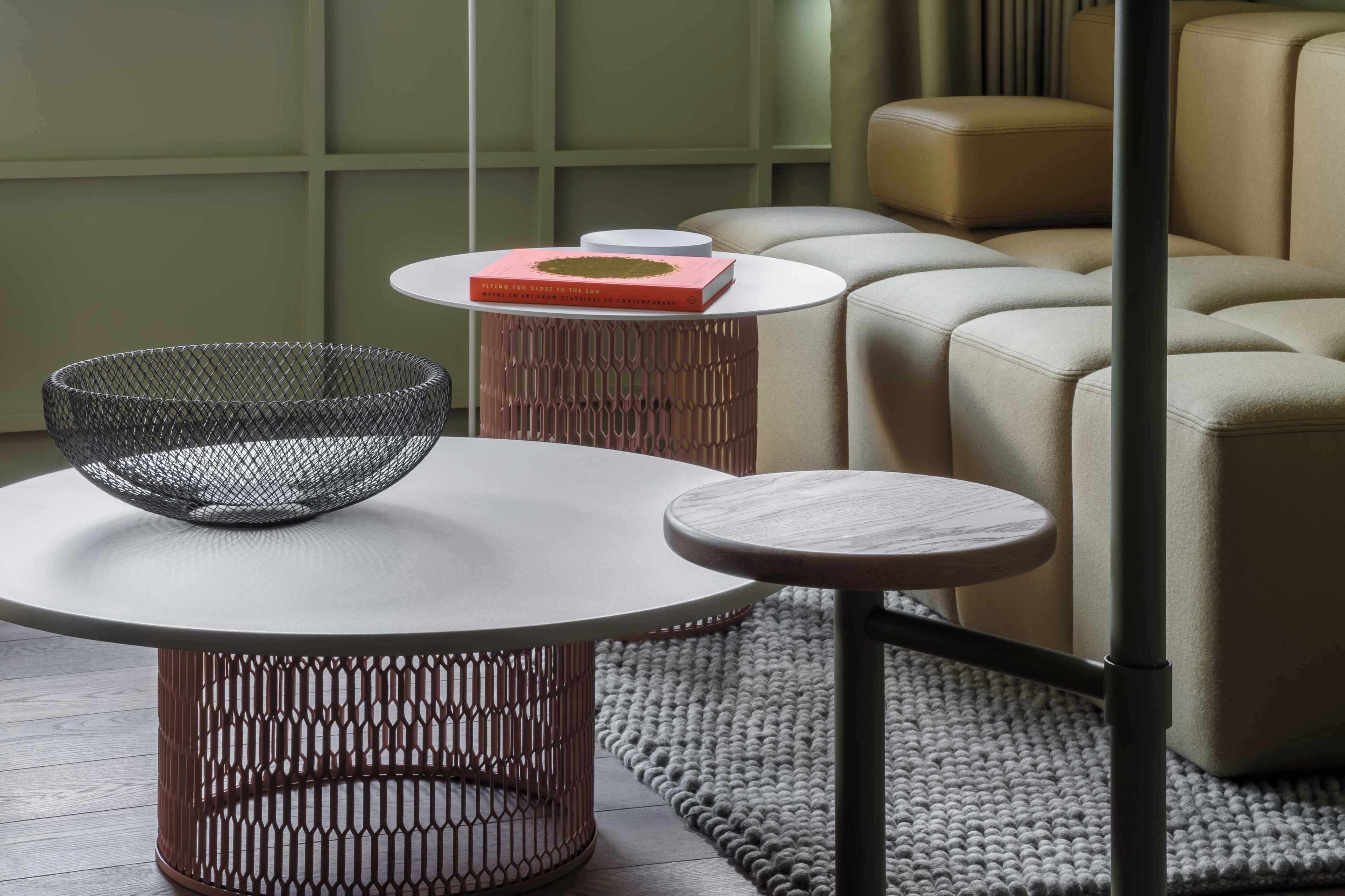 A modern living room with a round table, a wire basket, and a book on a side table.