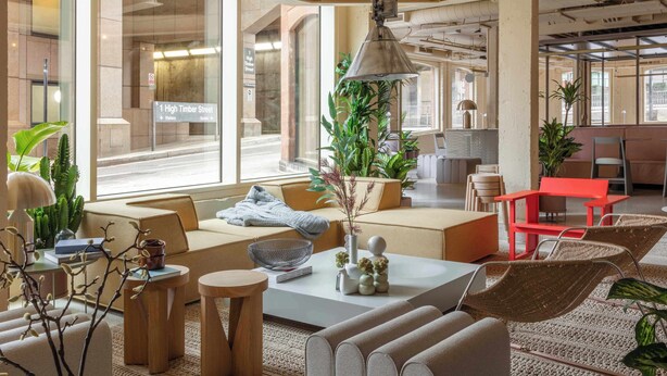 Een modern interieur met een bank, salontafel en stoelen, een hanglamp en grote ramen.