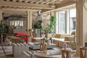 A modern living room with a sofa, chairs, a coffee table, and potted plants. - Locke At Broken Wharf (London)