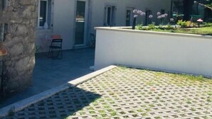 A building with a white facade, multiple windows, and a stone structure to the left. - B&B MonteCengio (Trieste)
