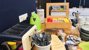 A kitchen counter with a toaster, a green kettle, a coffee maker, and various food items and utensils. - B&B MonteCengio (Trieste)