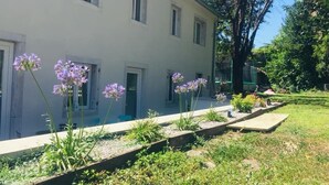 A white building with multiple windows and a garden with purple flowers. - B&B MonteCengio (Trieste)