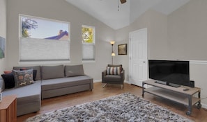 Relax in this stylish living room with a grey sofa, armchair, and large flat-screen TV.