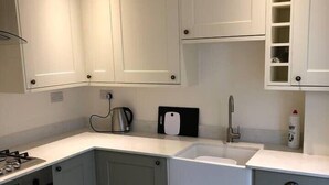 Een moderne keuken met grijze kastjes, een inbouwoven, een spoelbak en een waterkoker.
