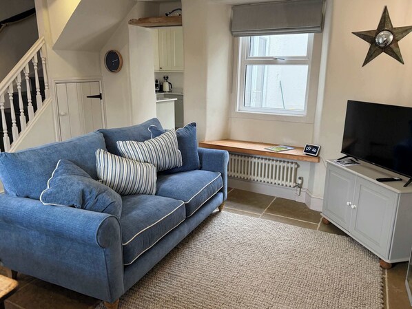 A living room with a blue sofa, a television, a star decoration, and a window.