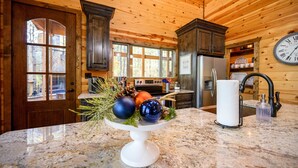 A kitchen with wooden walls, a marble countertop, a clock, and a decorative bowl with ornaments.