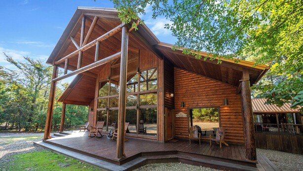 Uma cabana de tronco com um alpendre amplo e área de estar externa.